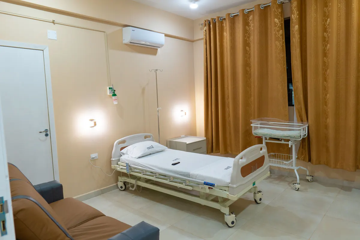 Habitación de internación con cama articulada, cuna y sillón para acompañante